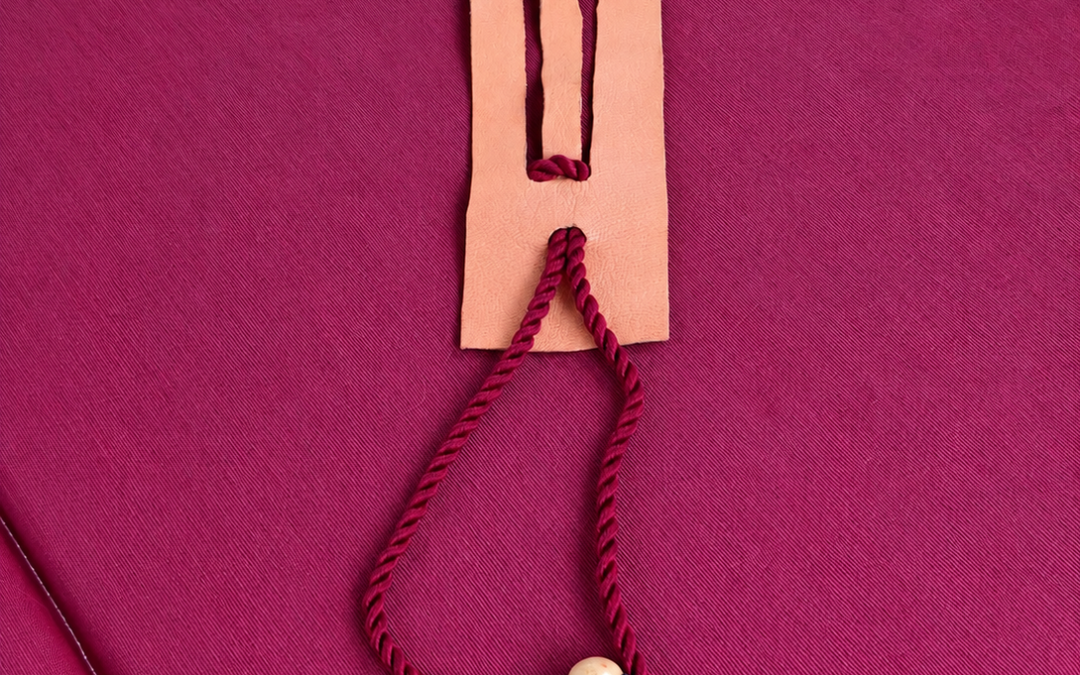 Reto de cuerda roja con dos cuentas de madera y una placa con ranuras