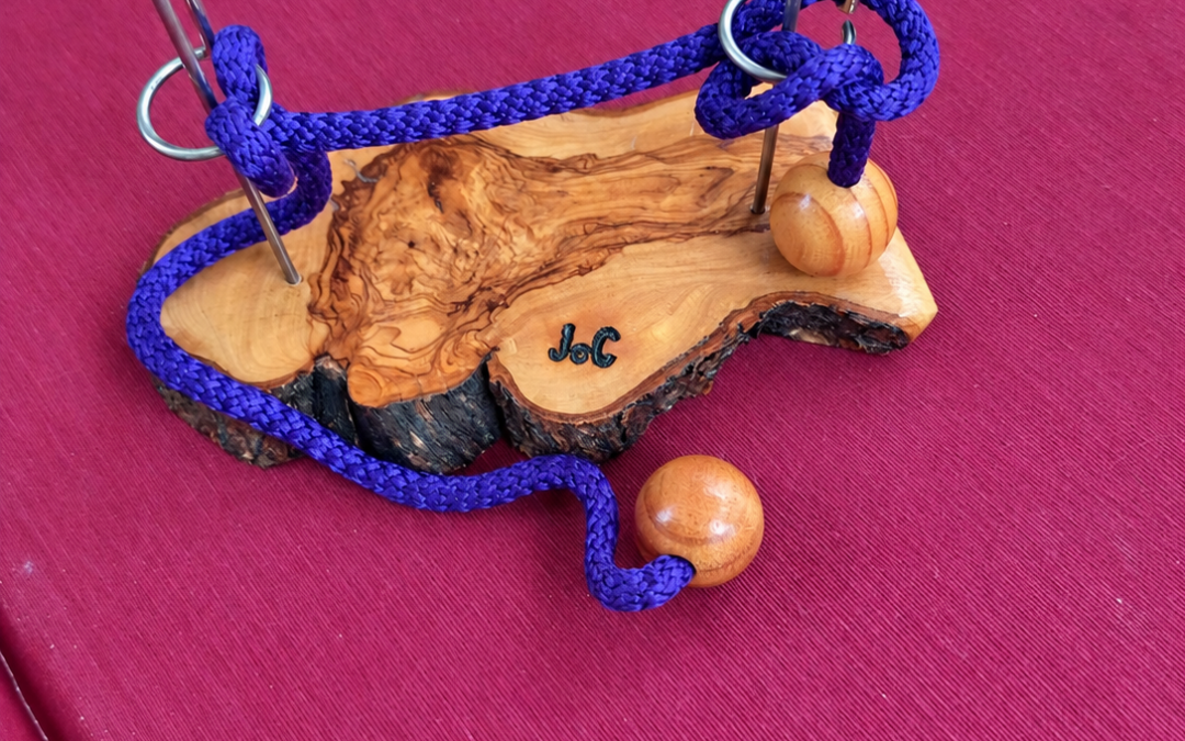 Rompecabezas de madera con cuerda morada, dos argollas metálicas y cuentas de madera